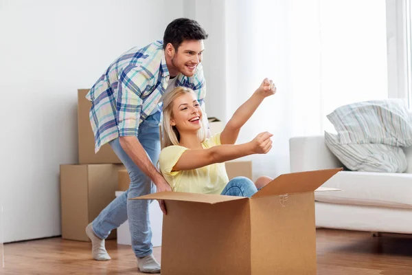 Feliz pareja divirtiéndose con caja en nuevo hogar — Foto de Stock