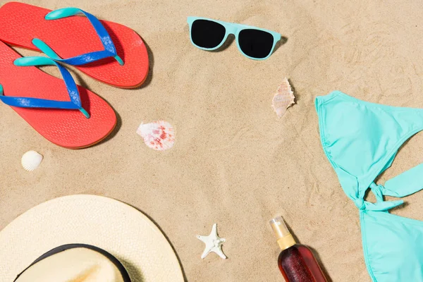 Słomkowy kapelusz, klapki i okulary przeciwsłoneczne na piasku plażowym — Zdjęcie stockowe