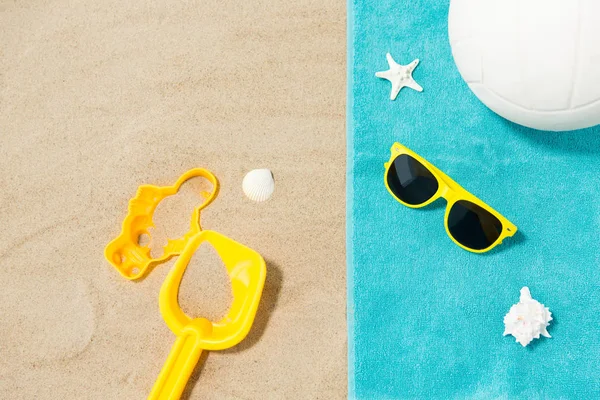 Sunglasses, sand toys and ball on beach towel — Stock Photo, Image