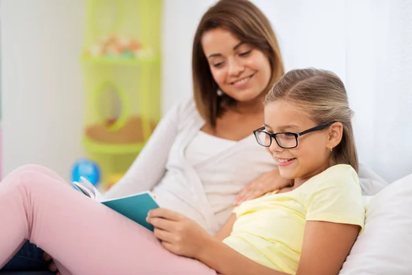 Glückliches Mädchen mit Mutter, die zu Hause Buch liest — Stockfoto