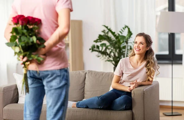 Mujer mirando al hombre con ramo de flores en casa —  Fotos de Stock
