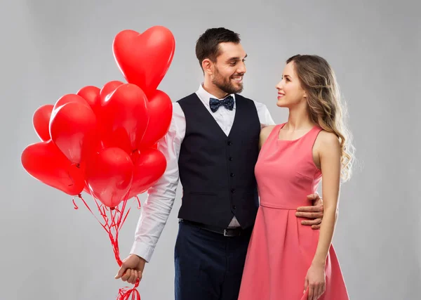 Ευτυχισμένο ζευγάρι με κόκκινη καρδιά σχήμα μπαλόνια — Φωτογραφία Αρχείου
