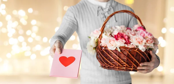 Hombre sosteniendo cesta de flores con tarjeta de felicitación — Foto de Stock