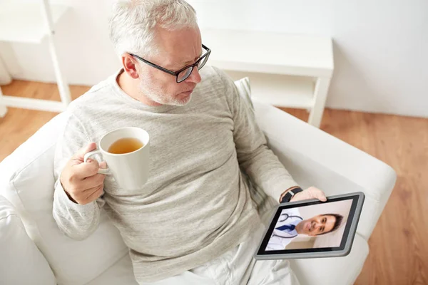 Старший чоловік має відеодзвінок з лікарем на планшеті — стокове фото