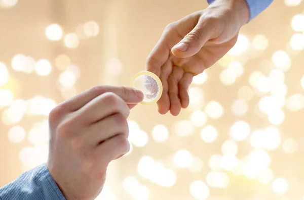 Close up of male gay couple hands giving condom — Stock Photo, Image