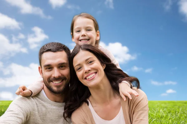 Familia feliz sobre el cielo azul y el fondo de hierba —  Fotos de Stock