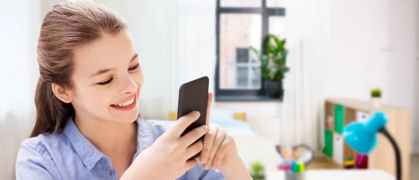 Mensagens menina sorridente no smartphone em casa — Fotografia de Stock