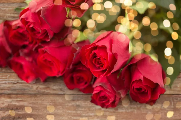 Κοντινό πλάνο του μπουκέτο κόκκινα τριαντάφυλλα πάνω από τα γιορτινά φώτα — Φωτογραφία Αρχείου