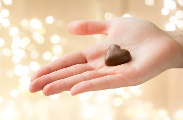 Close-up van de hand met hartvormige chocolade snoep — Stockfoto