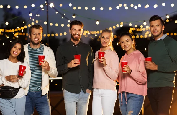 Amigos com copos de festa no telhado à noite — Fotografia de Stock