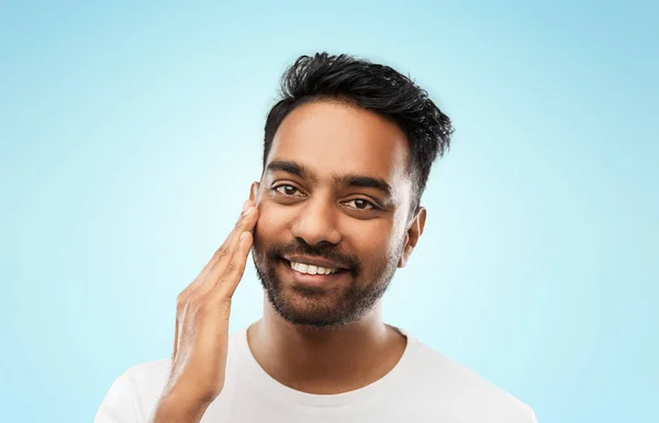 Lächelnder indischer Mann, der sein Gesicht berührt — Stockfoto