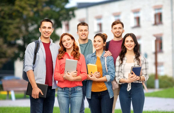 Skupina usmívající se studentů s knihami nad campus — Stock fotografie