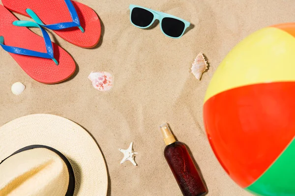 Hat, flip flops and shades and beach ball on sand — Stock Photo, Image