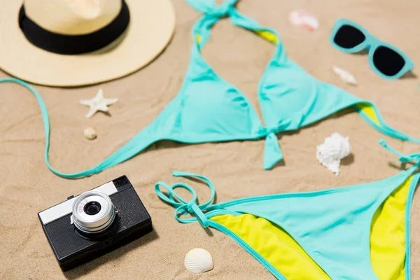 Bikini, kapelusz, aparat fotograficzny i okulary przeciwsłoneczne na plaży — Zdjęcie stockowe