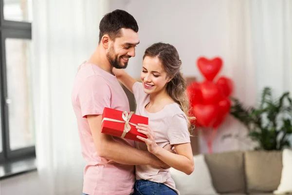 Gelukkige paar met cadeau doos knuffelen thuis — Stockfoto