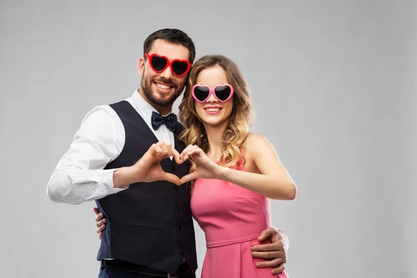 Pareja en gafas de sol haciendo gesto del corazón de la mano — Foto de Stock