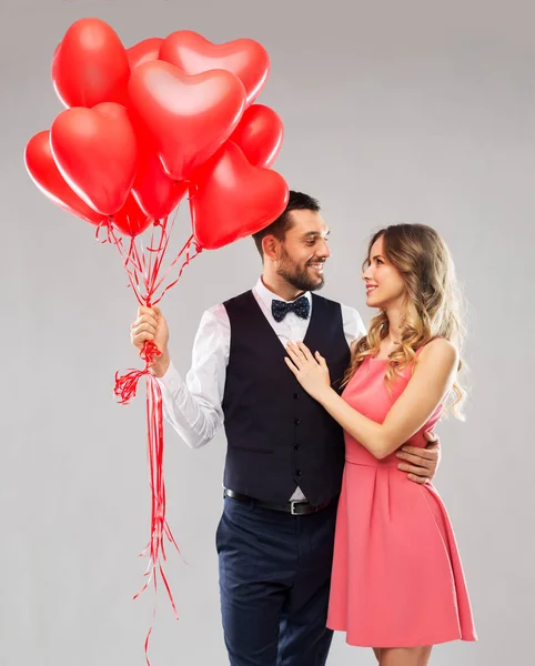 Счастливая пара с шариками в форме красного сердца — стоковое фото