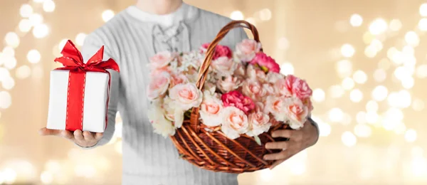 Man with basket of flowers and gift over lights — Stock Photo, Image