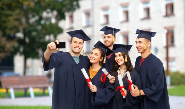 Diplomados com diplomas tirando selfie por celular — Fotografia de Stock