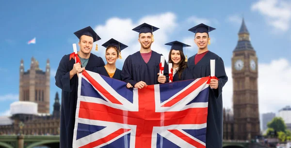 Absolventi s diplomy a britská vlajka — Stock fotografie