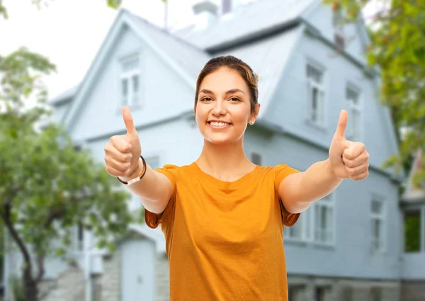 Teenage girl showing thumbs up over house — Stock Photo, Image