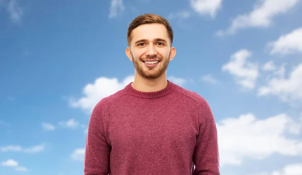Usměvavý mladý muž na pozadí modré oblohy — Stock fotografie