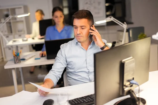 Hombre llamando en el teléfono inteligente en la oficina de noche — Foto de Stock