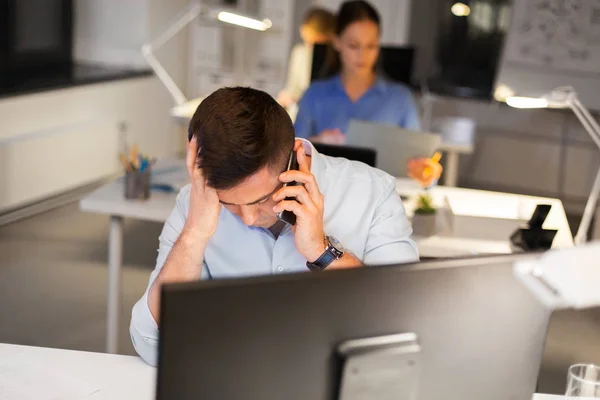 Stressed man calling on smartphone at night office — Stock Photo, Image