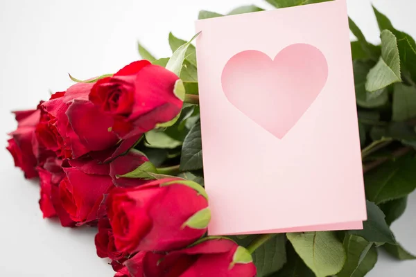 Close up de rosas vermelhas e cartão de saudação com coração — Fotografia de Stock