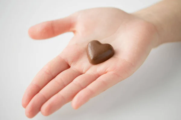Close up de mão com doces de chocolate em forma de coração — Fotografia de Stock