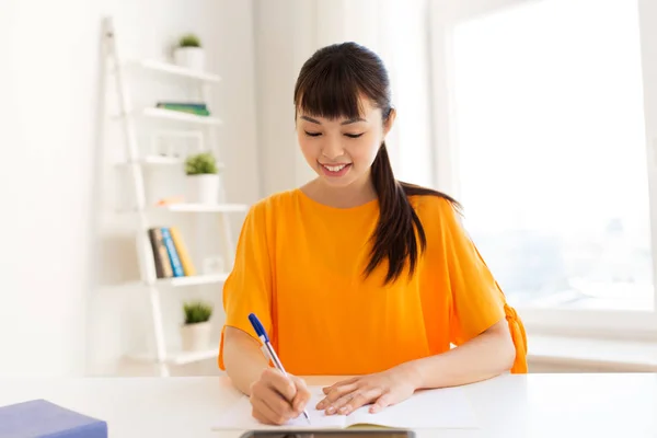 Asiático estudiante chica escritura a notebook en casa —  Fotos de Stock