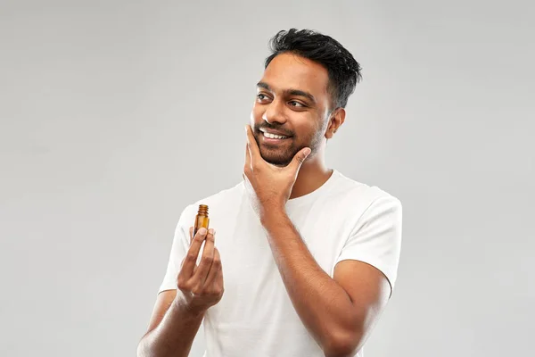 Homem índio sorrindo aplicando óleo de aliciamento à barba — Fotografia de Stock