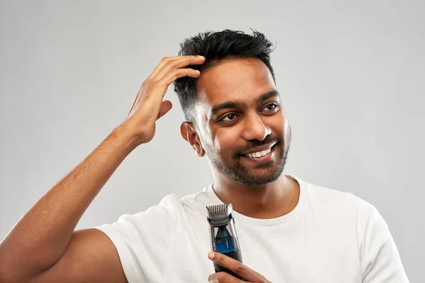 Uomo indiano sorridente con trimmer toccare i capelli — Foto Stock