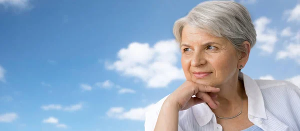 Портрет задумчивой пожилой женщины над голубым небом — стоковое фото