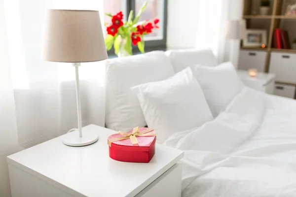 寝室のベッドサイド テーブルの上のハートの形のギフト — ストック写真
