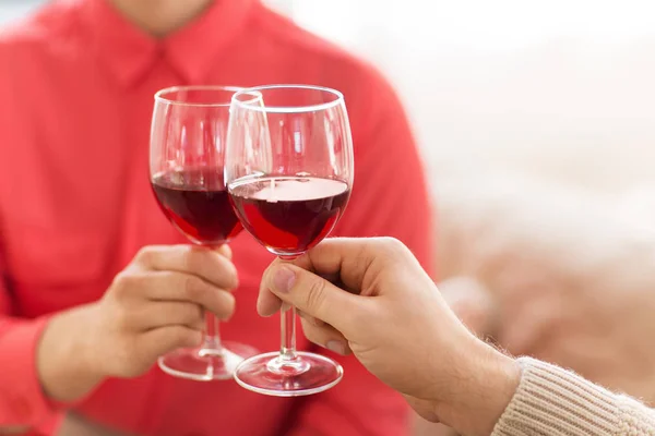 Hands of couple clinking red wine glasses — Stock Photo, Image