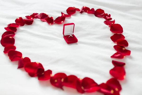 Herz aus Blütenblättern und Diamantring in Geschenkbox — Stockfoto