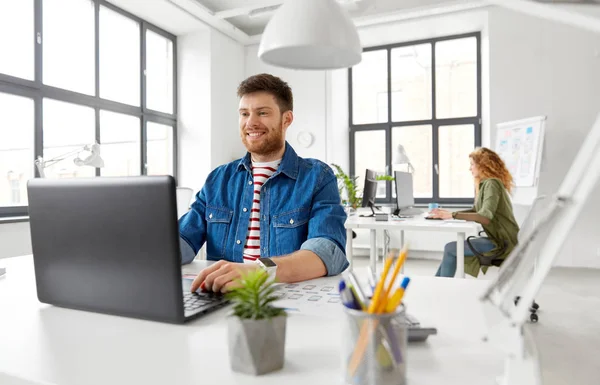 Ofiste çalışan dizüstü bilgisayar ile yaratıcı adam gülümseyen — Stok fotoğraf