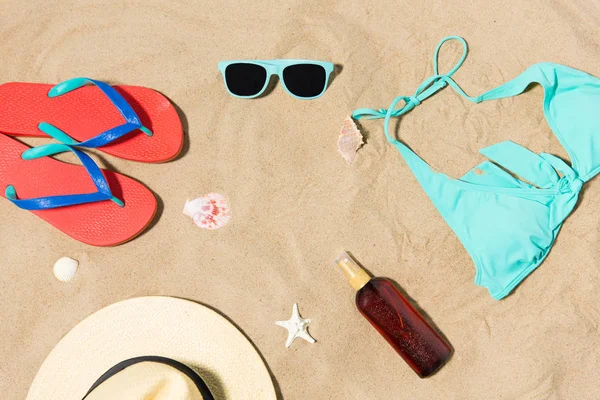 Słomkowy kapelusz, klapki i okulary przeciwsłoneczne na piasku plażowym — Zdjęcie stockowe