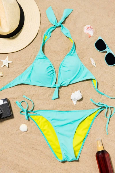 Bikini, hat, camera and sunglasses on beach sand — Stock Photo, Image