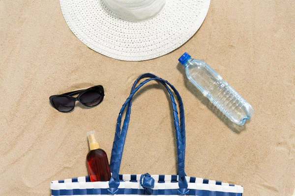 Bolsa de playa, protector solar, gafas de sol y sombrero en la arena Fotos De Stock