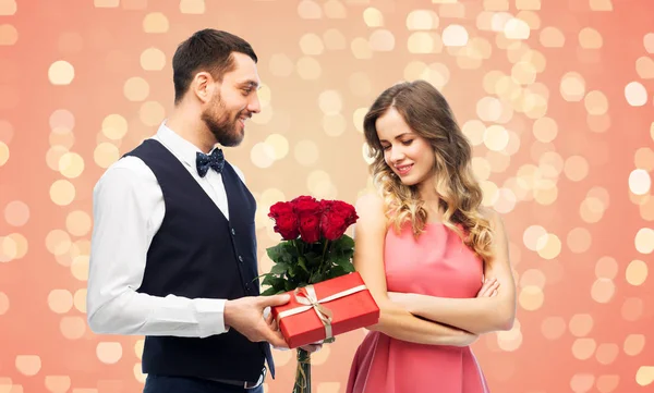 Happy man giving woman flowers and present — Stock Photo, Image