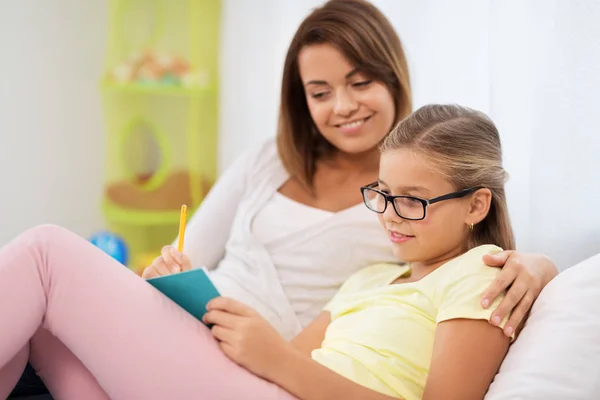 Glad tjej med mor skriver till notebook hemma — Stockfoto