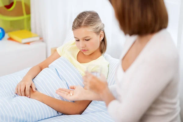 Mother giving medicine to ill daughter at home — Stock Photo, Image