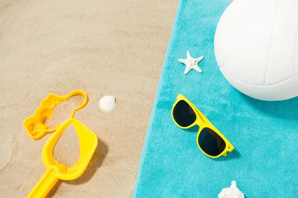 Okulary przeciwsłoneczne, zabawki z piasku i piłka na ręczniku plażowym — Zdjęcie stockowe
