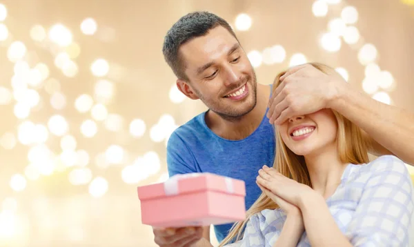 Sonriente hombre sorprende a su novia con presente — Foto de Stock