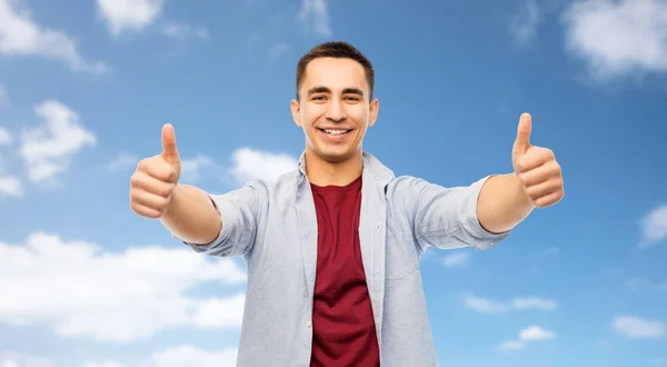 Happy young man showing thumbs up over blue sky — Stock Photo, Image
