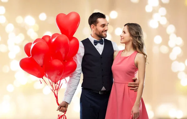 Casal feliz com balões em forma de coração vermelho — Fotografia de Stock