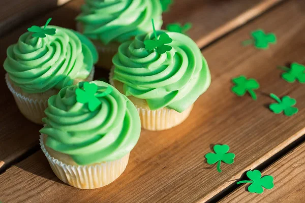 나무 식탁 위의 초록빛 컵 케익과 샴록 — 스톡 사진