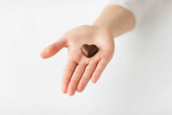 Крупним планом рука з шоколадними цукерками у формі серця — стокове фото